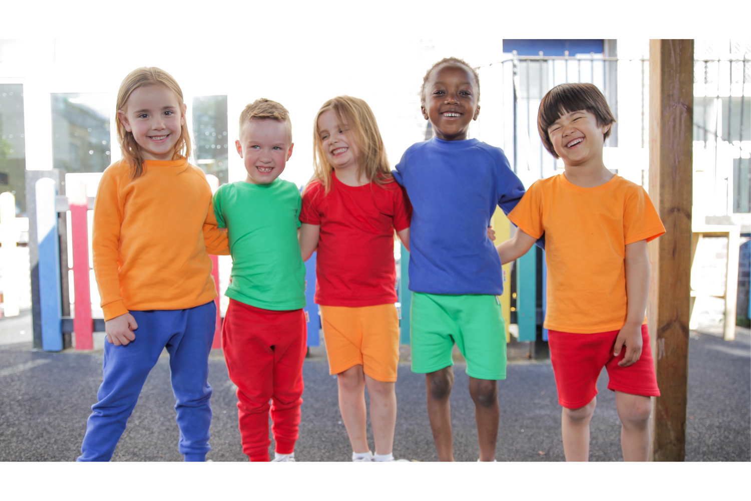 Five kids wearing Hues Clothing with their arms around each other standing in a playground