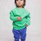 A toddler wearing a green jumper and blue joggers - Hues Clothing