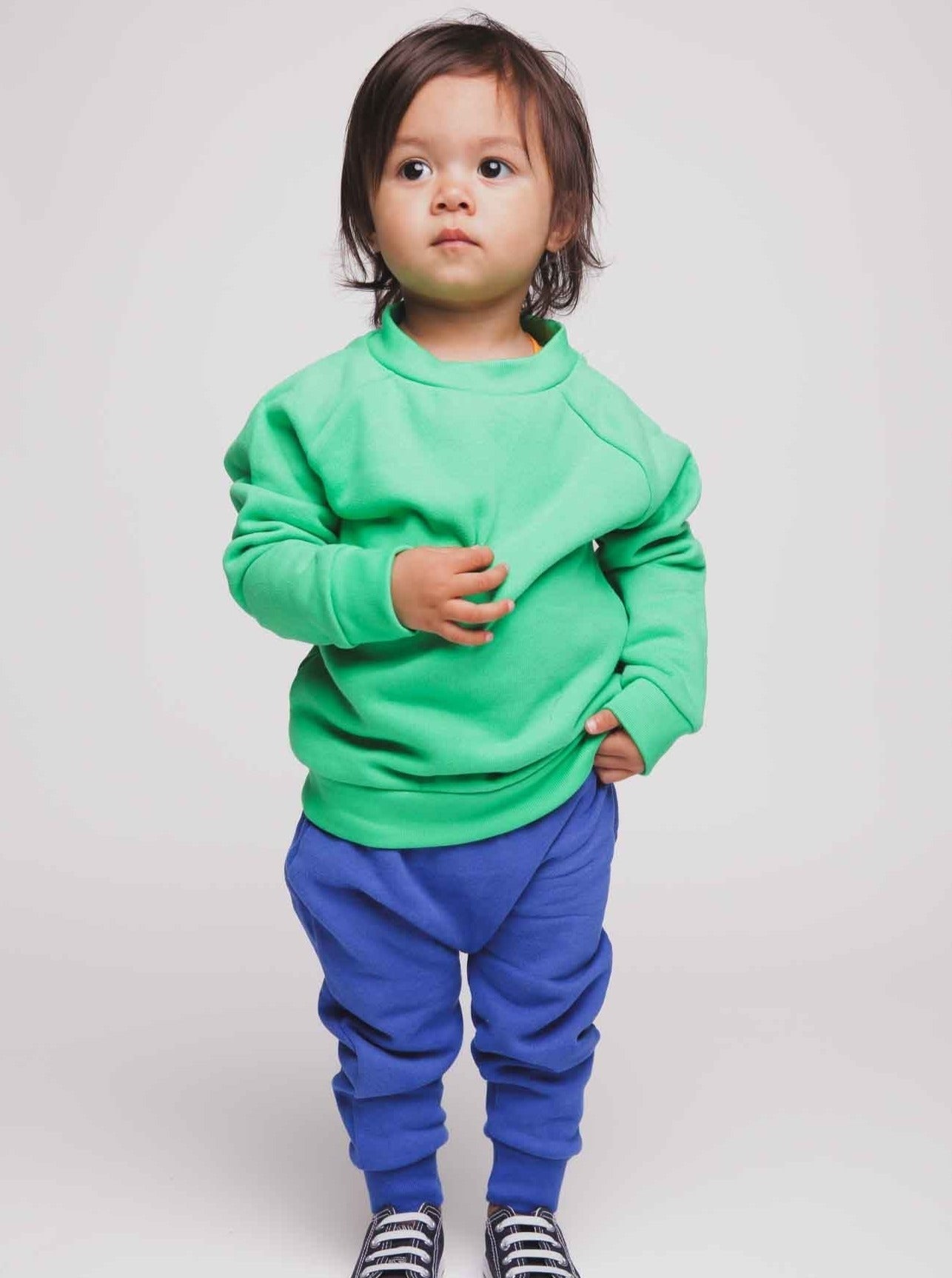 A toddler wearing a green jumper and blue joggers - Hues Clothing