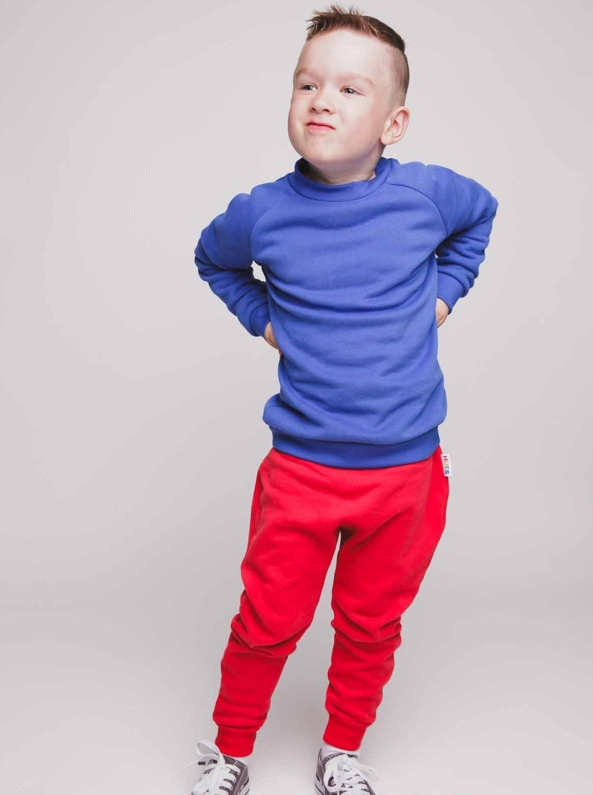 A boy wearing a blue jumper and red joggers - Hues Clothing