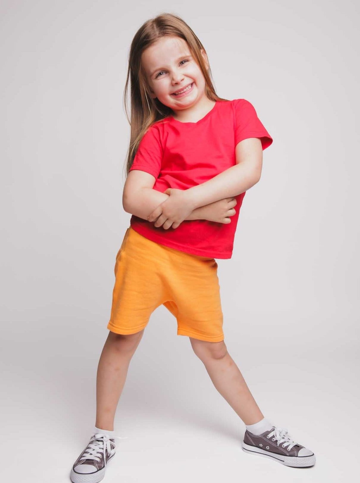 A girl wearing a red t-shirt and orange shorts - Hues Clothing