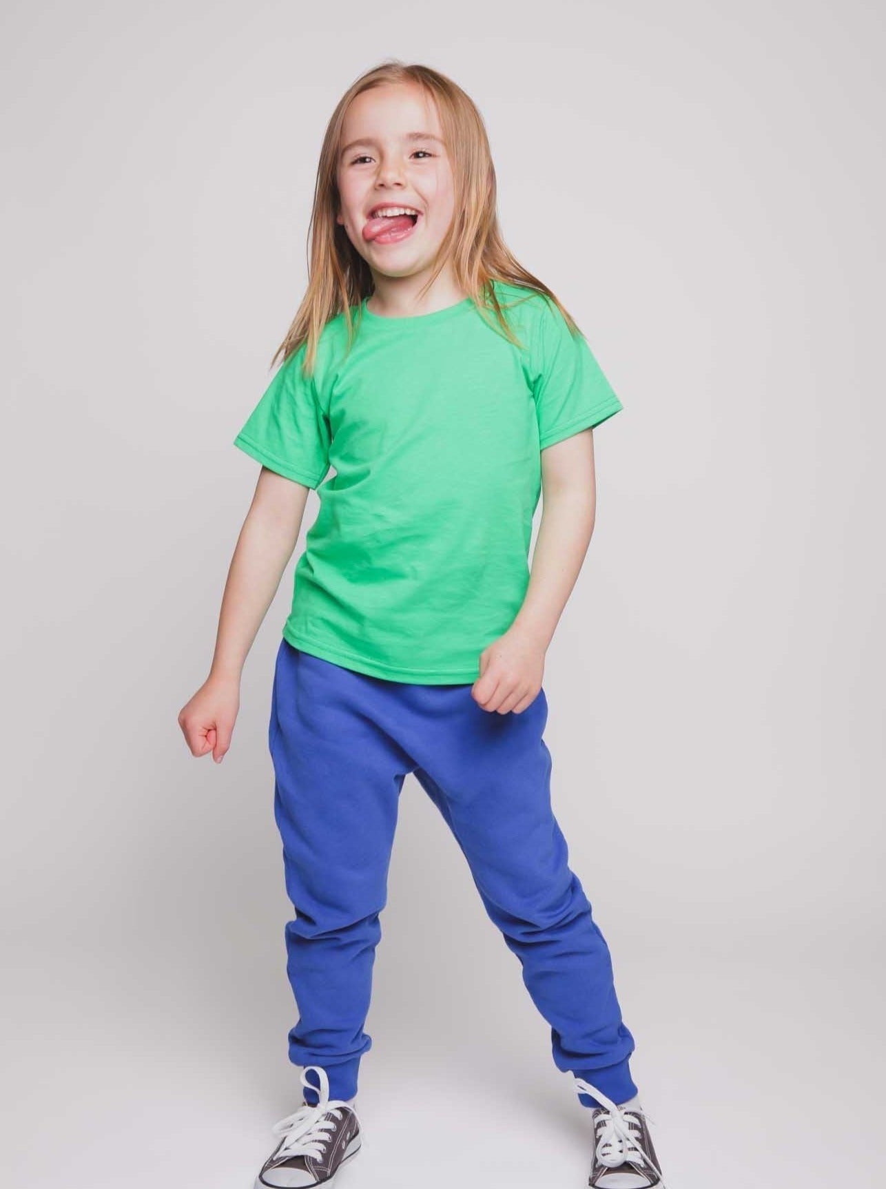 A blonde haired girl wearing a green t-shirt and blue trousers - Hues Clothing